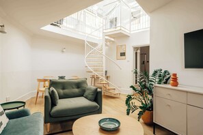 A spacious living area with a modern staircase, a dining table, and a sofa. - The Regency: Amazing 2BR with workspace, Victoria (London)