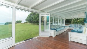 A covered outdoor seating area with a view of a grassy field and trees.