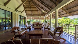 A covered outdoor seating area with wooden furniture and a view of greenery. - Oasis Cocotal: Family 4BR Apartment in Punta Cana (Punta Cana)