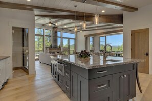 Een ruime keuken met een groot eiland, moderne apparatuur en uitzicht op de omgeving.
