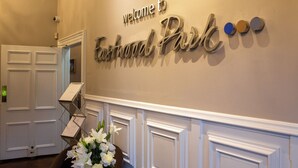 Een receptiegedeelte met een bord waarop 'Welcome to Eastwood Park' staat, een trap en een bloemstuk.
