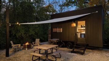 A rustic outdoor seating area with a fire pit, wooden furniture, and a covered patio.