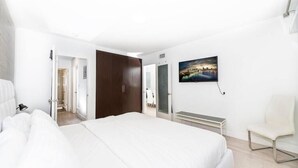Quarto de hotel com uma cama grande, uma escrivaninha, uma cadeira e um quadro na parede.