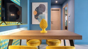 A modern dining area with a wooden table, yellow chairs, a decorative yellow object, and abstract wall art. - Comfortable apartment in Sorrento center (Sorrento)