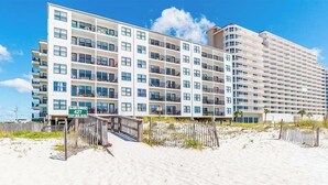 A multi-story hotel with a beachside location, featuring balconies and a clear view of the ocean.