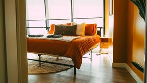 Ein modernes Schlafzimmer mit einem großen Bett, einem Nachttisch und Blick durch ein Fenster.