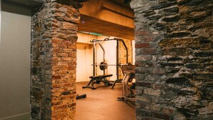 Ein steinernes Tor führt zu einem Fitnessraum mit Trainingsgeräten.