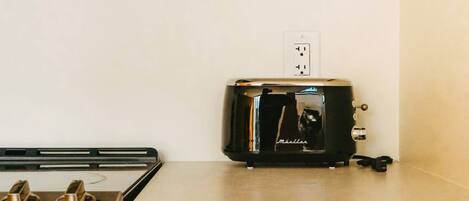 Una cucina con microonde, tostapane, fornello e un cassetto con maniglia dorata.
