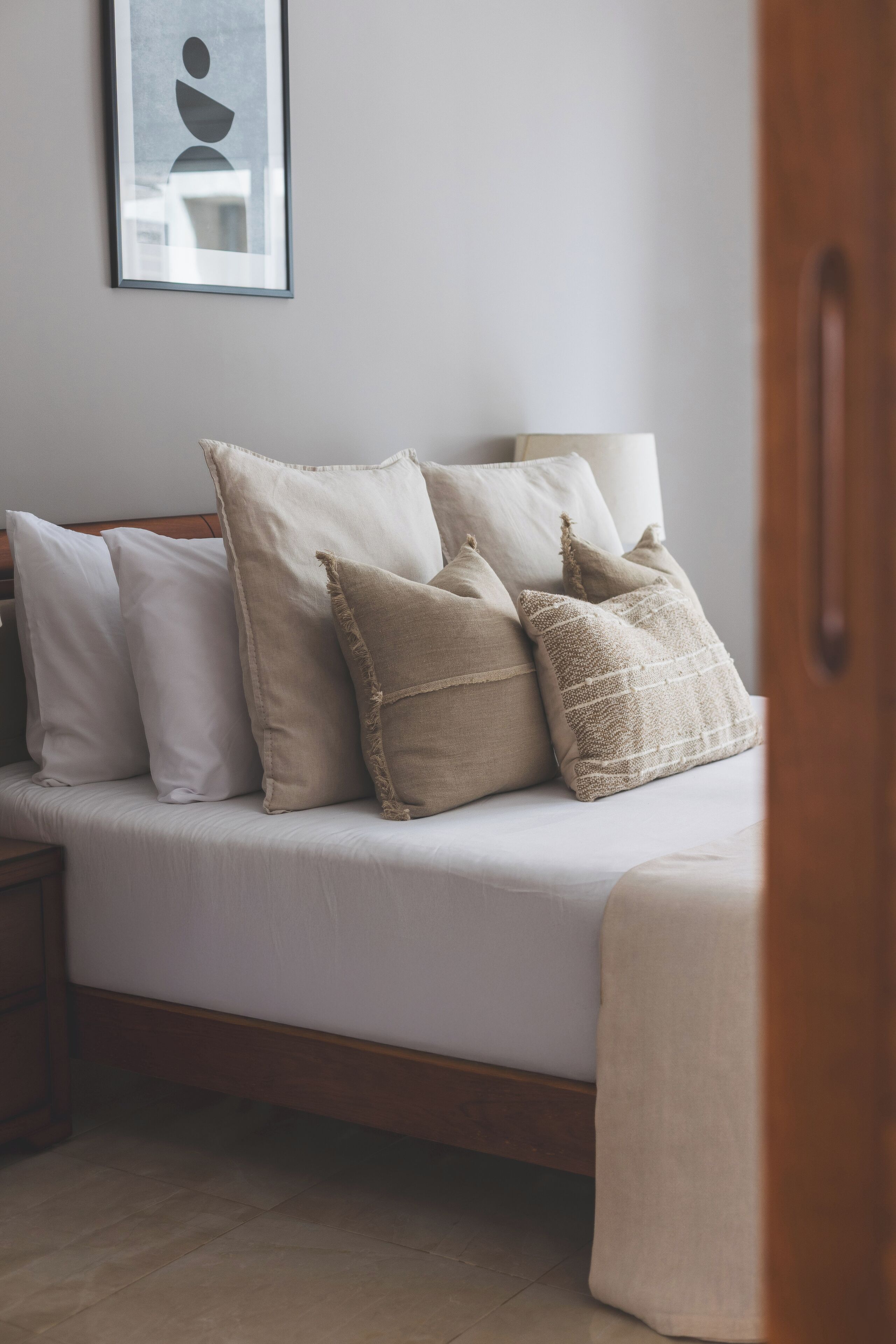 A neatly made bed with a variety of pillows and a bedside table.