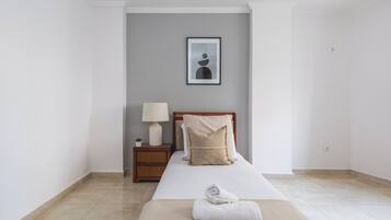 Habitación de hotel con cama, mesita de noche con lámpara y un cuadro en la pared.
