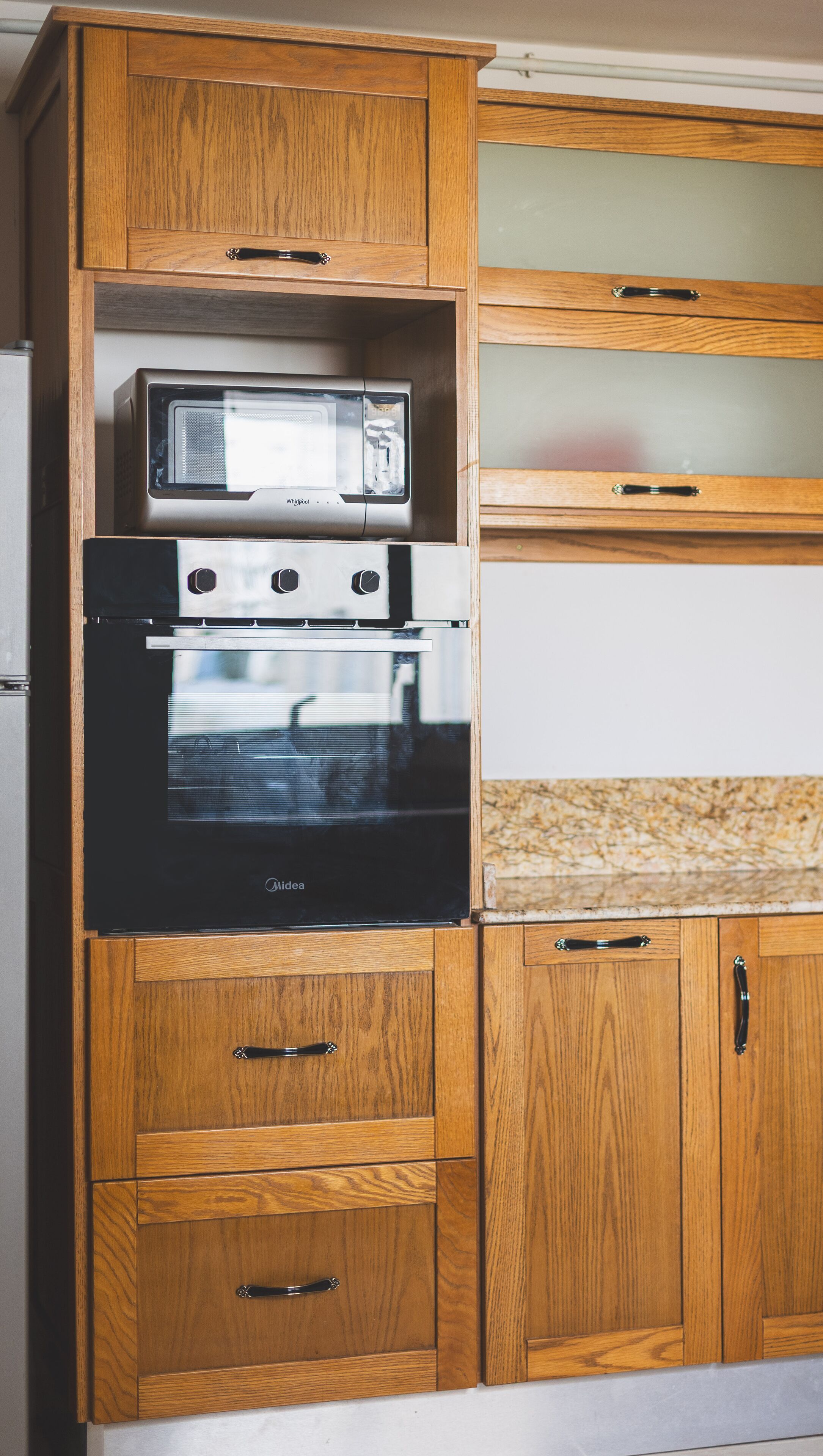 Eine Küche mit Holzausstattung, einer eingebauten Mikrowelle und einem Midway-Backofen.