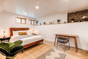 Une chambre à coucher avec un lit en bois, un bureau, une chaise et une étagère ornée d’objets décoratifs.
