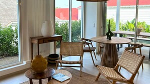 Une pièce spacieuse avec de grandes fenêtres, des meubles en osier et des lampes suspendues.