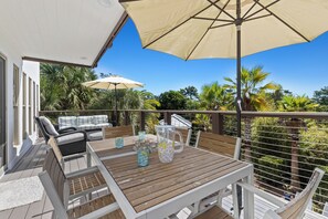 A wooden deck with a table, chairs, and umbrellas.