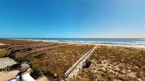 A beach with a wooden boardwalk leading to the water.