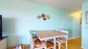 Un coin repas avec une table en bois et des chaises blanches, un mur bleu clair et une décoration murale.