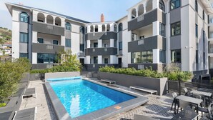 Un bâtiment moderne doté d’une piscine, d’un espace extérieur aménagé et de plusieurs balcons.
