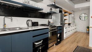 A modern kitchen with built-in appliances, a sink, and a wooden floor.