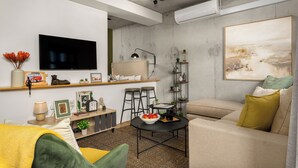 A living room with a sofa, a coffee table, a TV, and a painting on the wall.