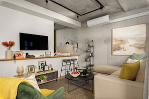 A living room with a sofa, a coffee table, a TV, and a painting on the wall.