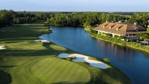 Ein Golfplatz mit Clubhaus neben einem See.