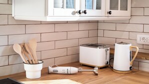 A kitchen with white cabinets, a toaster, a kettle, and wooden utensils. - Boutique House Rustikana with pool Korte (Izola)