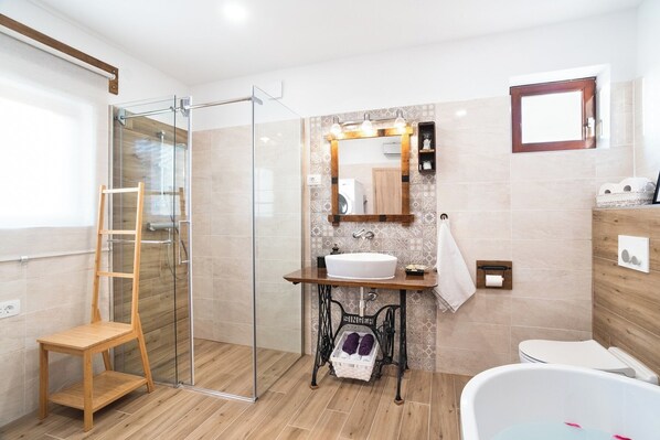 Ein modernes Badezimmer mit Duschkabine aus Glas, einem Holzbadezimmer-Möbel, einem Waschbecken und einer Badewanne.