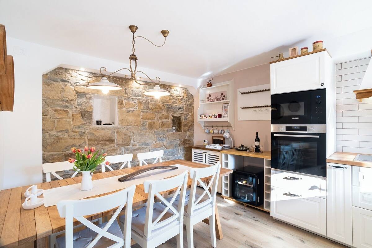 A modern kitchen with a stone wall, white cabinetry, and a Bosch oven.