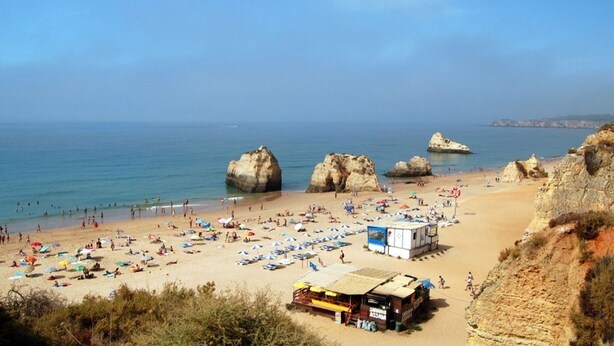 A beach with large rock formations, a lifeguard station, and beach umbrellas. - Linaria Apartment, Portimão, Algarve (Portimão)