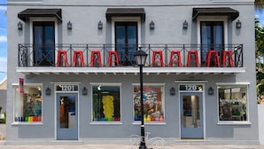 A two-story building with a balcony, numbered 1201 and 120, featuring storefronts with colorful displays. - Yellowfin Ledge | Ideal Getaway On Duval! Balcony (Key West)