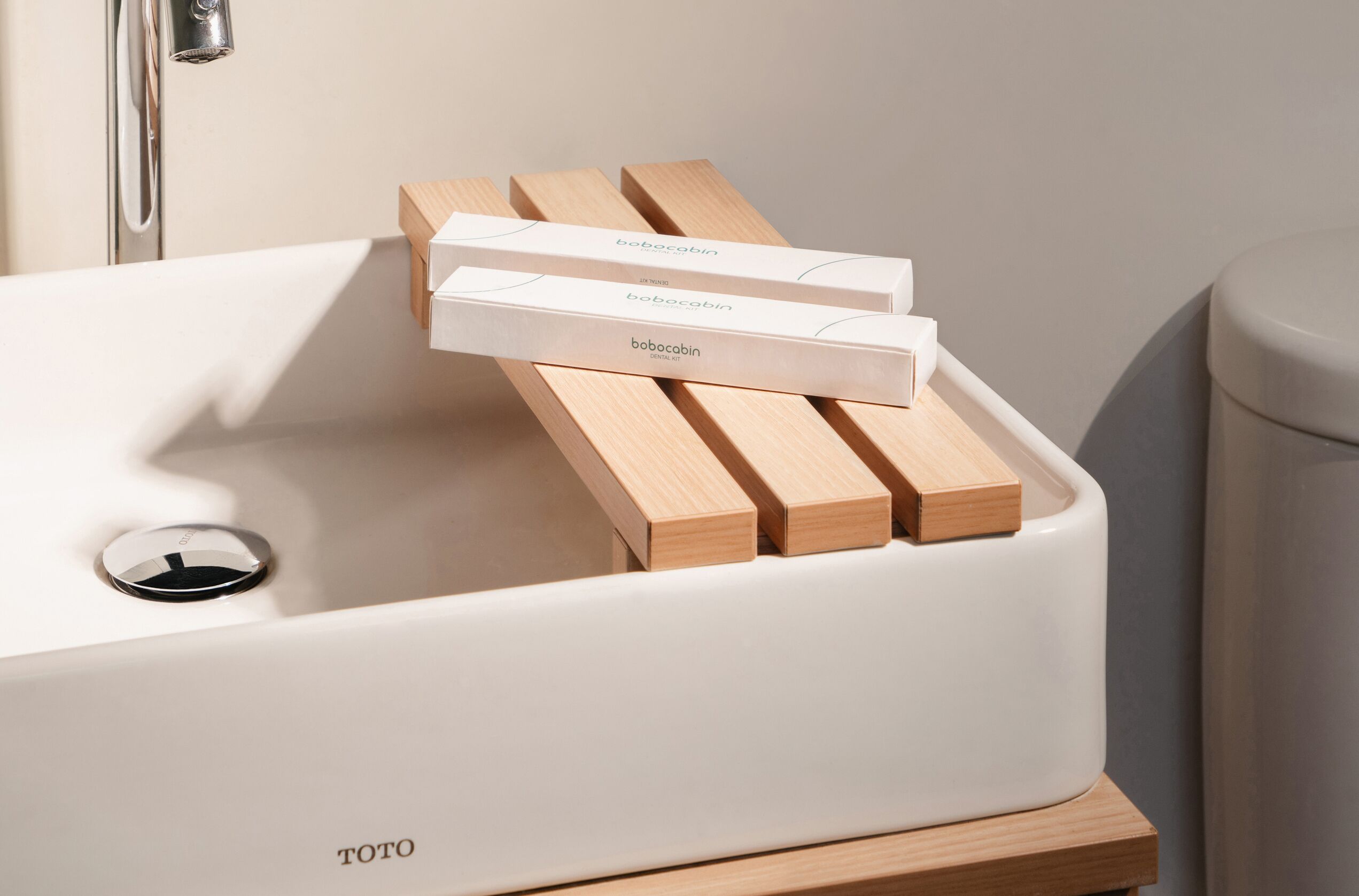 A white bathtub with wooden side panels and three white boxes labeled "bobocabin" on a wooden platform.
