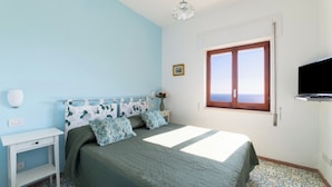 A bedroom with a bed, a nightstand, a wall-mounted TV, a window, and a patterned floor. - MAIN Roof Terrace Apartment (Massa Lubrense)