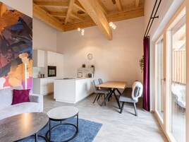 Una cocina moderna con armarios blancos, una isla central y un comedor con mesa y sillas de madera.