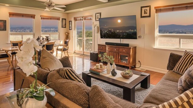 A spacious living room with a large flat-screen TV, comfortable seating, and a view of the city at sunset. - Spacious 3BR/2.5BA Home • 2800 sq ft • Mountain Views & Prime Location. PRIVATE. (Newbury Park)