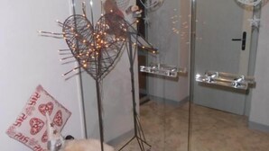 A room with a glass partition, a decorative metal sculpture, a plush toy, and a heart-shaped cushion. - Hotel Escher (Leukerbad)