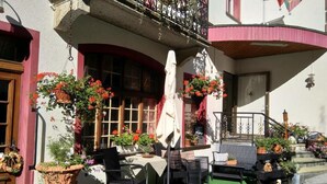 An outdoor seating area with tables and chairs, surrounded by potted plants and flowers. - Hotel Escher (Leukerbad)