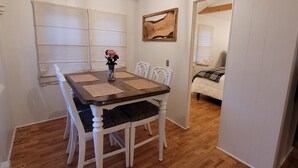 Un comedor con una mesa de madera, sillas blancas y una lámpara colgante.