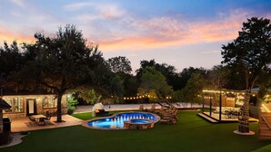 A well-lit outdoor area with a swimming pool, seating, and a covered patio area. - La Mariposa ~ Grand Oasis Big Luxury Home (Sunset Valley Austin)
