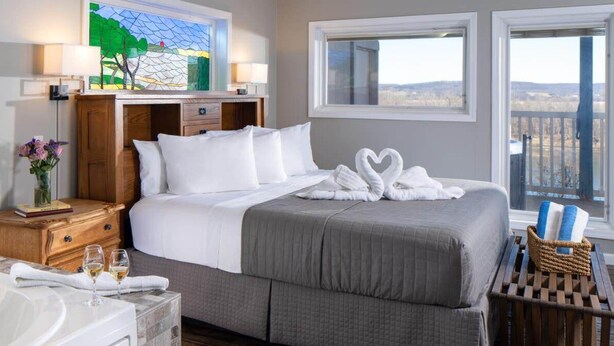 A hotel room with a large bed, a bathtub, and a view of the outdoors.