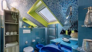 Ein modernes Badezimmer mit blauen Fliesen, einem Oberlicht, einem großen Waschbecken und einer Toilette.