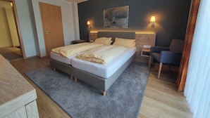 Een moderne slaapkamer met een tweepersoonsbed, nachtkastjes, een bureau en een stoel.