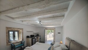 Un dormitorio con cama, escritorio, lavadora y una pequeña kitchenette.