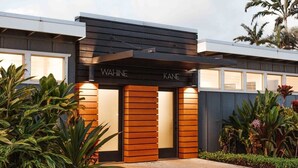 A modern building with a black facade and the name "WAHINE KANE" displayed prominently. - Oceanview Cottage | Walk to Poipu & Brennecke's Beach (Koloa)