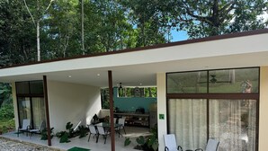 A modern house with a covered patio area, large windows, and a view of the surrounding greenery.