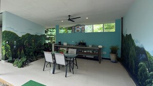 A dining area with a table and chairs, a ceiling fan, and a window with a view of greenery.