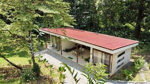 A modern house with a red roof, large windows, and a covered patio area.