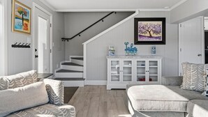 Ein modernes Wohnzimmer mit Treppe, einem weißen Schrank mit Glastüren und einem gerahmten Bild an der Wand.