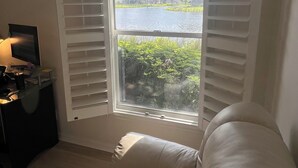 A room with a large window, a sofa, and a desk with a computer. - Charming Pool House with a nearly 600 sq/ft Private Efficiency Suite Inside  (Bonita Springs)