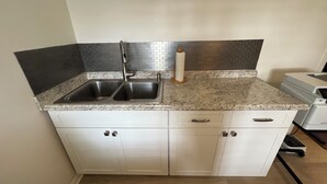 A kitchen with two stainless steel sinks, a granite countertop, and white cabinets. - Charming Pool House with a nearly 600 sq/ft Private Efficiency Suite Inside  (Bonita Springs)