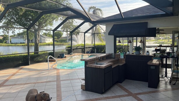A covered outdoor area with a pool, a bar, and a view of a lake. - Charming Pool House with a nearly 600 sq/ft Private Efficiency Suite Inside  (Bonita Springs)